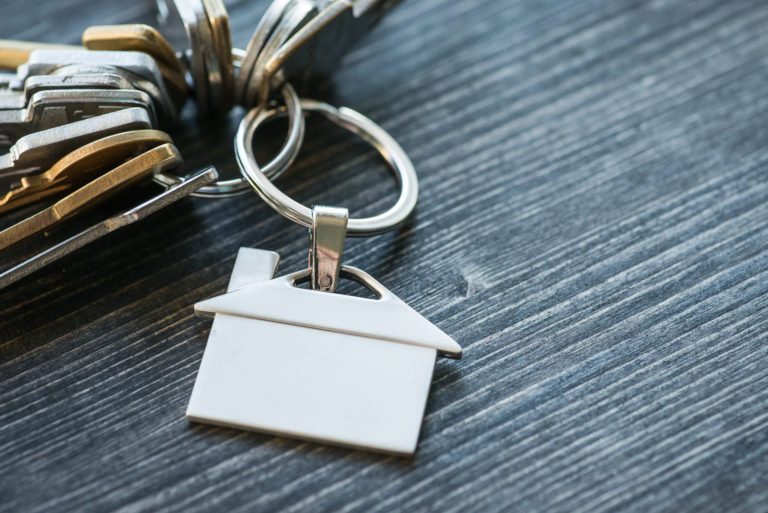 Bunch of keys with house shaped key ring on a wooden table